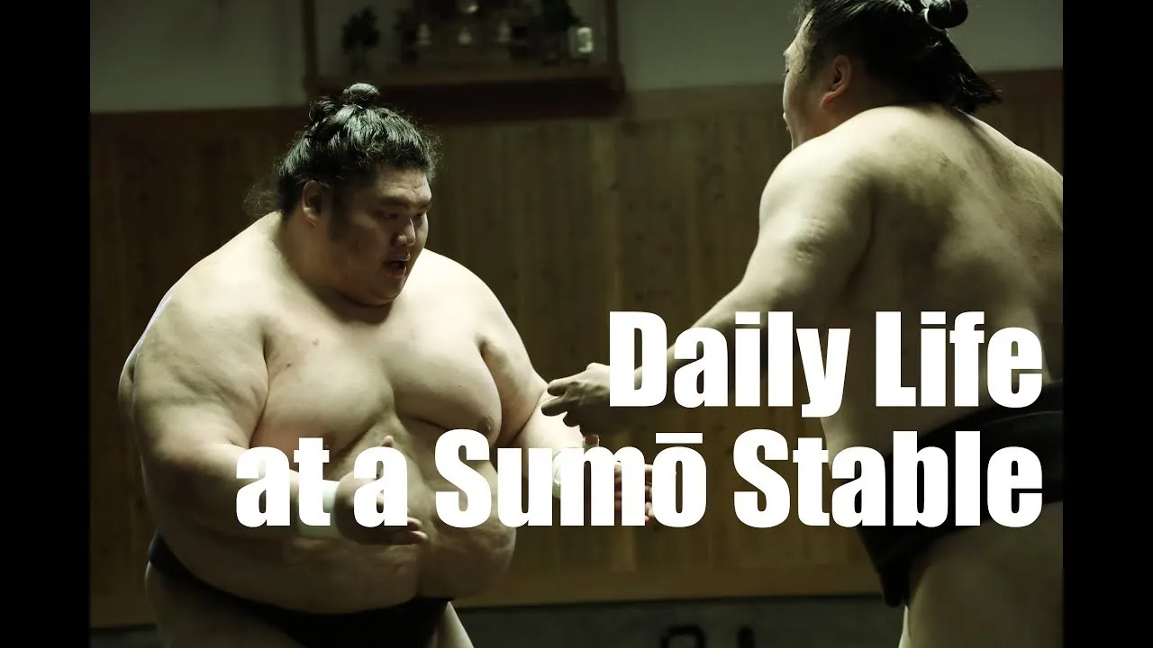 Two sumo wrestlers face each other during practice with “Daily Life at a Sumō Stable” overlaid.